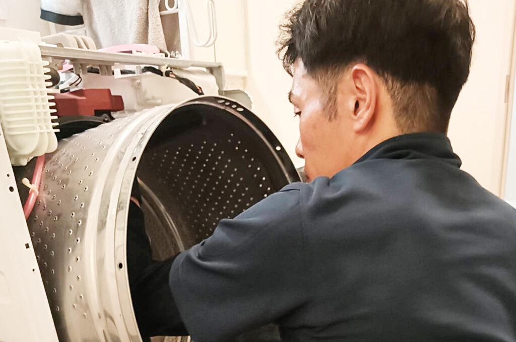 ドラム式洗濯機を清掃している男性
